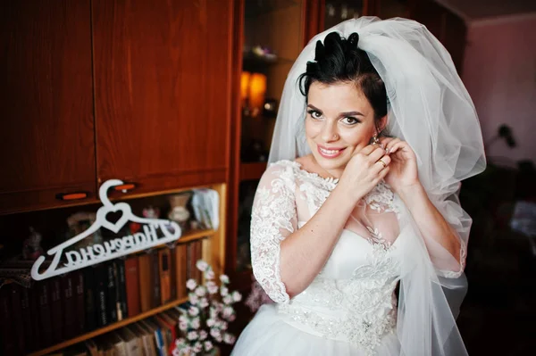 美しい花嫁のウェディング ドレスの自分の部屋でイヤリングに入れて — ストック写真