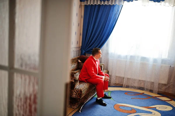 Όμορφος groom σε κόκκινο σμόκιν ποζάρει στο δωμάτιό του για την ημέρα του γάμου — Φωτογραφία Αρχείου
