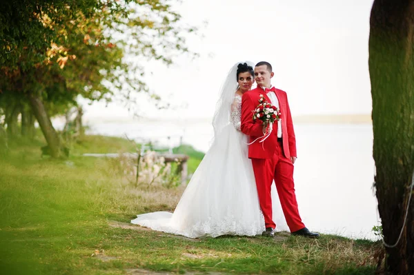 Superbe couple de mariage avec un bouquet étreignant au bord du lac . — Photo