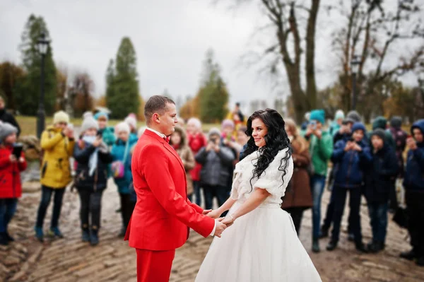 Hermosa pareja de boda cogidas de la mano en el pavimento mientras cuervo — Foto de Stock