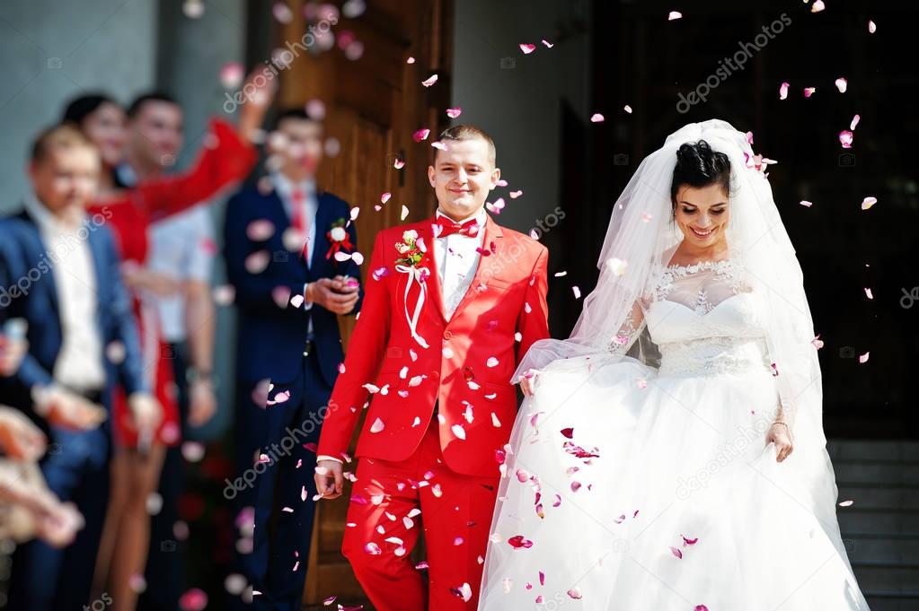 Fabulous wedding couple walking out of the church and people thr