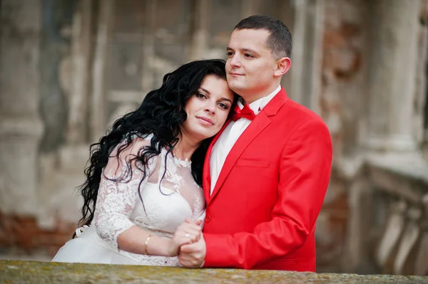 Nahaufnahme eines hübschen Bräutigams im roten Smoking, der seine Frau hält — Stockfoto