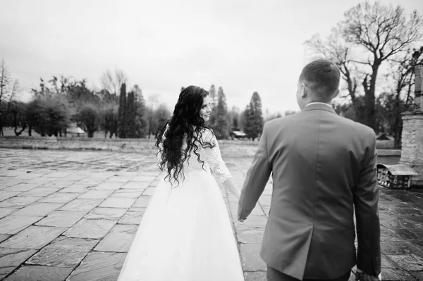 Hermosa pareja de boda caminando sobre el pavimento en una lluvia y —  Fotos de Stock