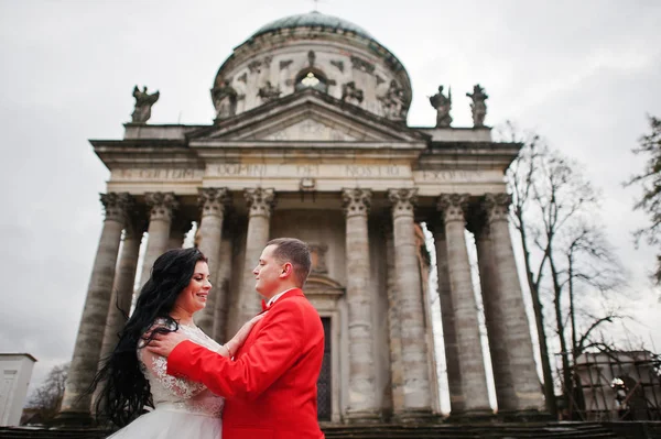 Para ślub przytulanie przed barokowym chucrh w tle. — Zdjęcie stockowe