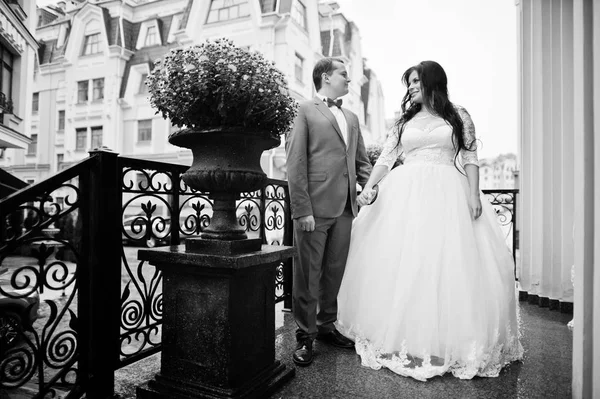 Hochzeitspaar hält Händchen auf der Terrasse mit Blumen in der Hand — Stockfoto