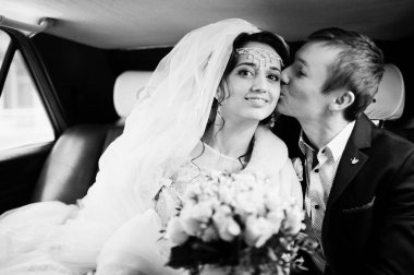 Poz ve arabada öpüşme muhteşem Düğün çifti. Siyah ve