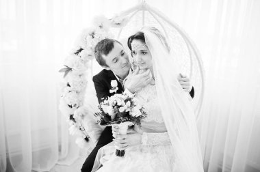 Evlilik çift stüdyoda çiçek salıncak üzerinde oturuyor. Siyah 