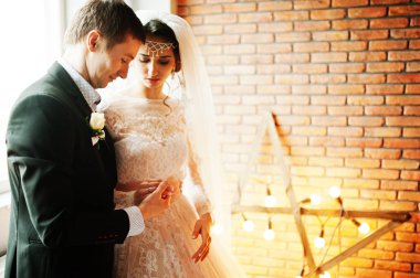 Çift yıldız şeklinde ışık ile tuğla duvara poz düğün.