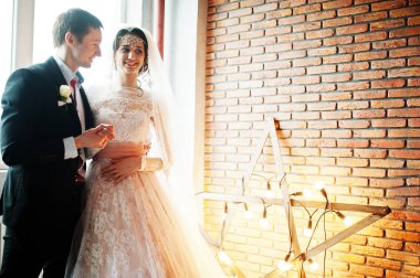 Çift yıldız şeklinde ışık ile tuğla duvara poz düğün.