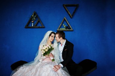 Triangula ile mavi duvara oturan muhteşem Düğün çifti