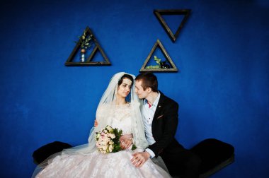 Triangula ile mavi duvara oturan muhteşem Düğün çifti