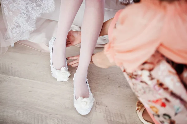 Подружка невесты помогает невесте надеть свадебные туфли и получить Реа — стоковое фото
