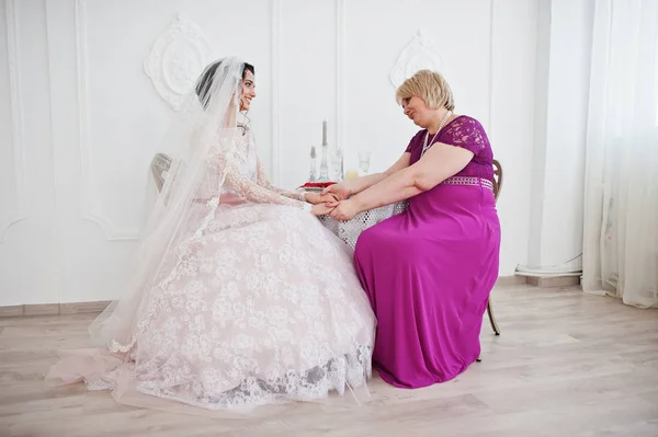 Прекрасная невеста в свадебном платье позирует со своей матерью в фиолетовом — стоковое фото