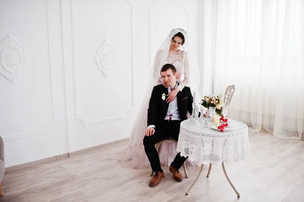 Attractive bride standing next to the groom while he is sitting — Stock Photo, Image