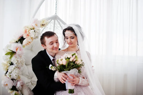Γαμήλιο ζεύγος κάθεται στο floral ταλάντευση στο στούντιο. — Φωτογραφία Αρχείου