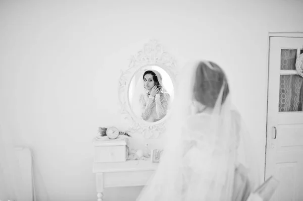 Hermosa novia poniéndose sus pendientes de boda en la habitación en f — Foto de Stock