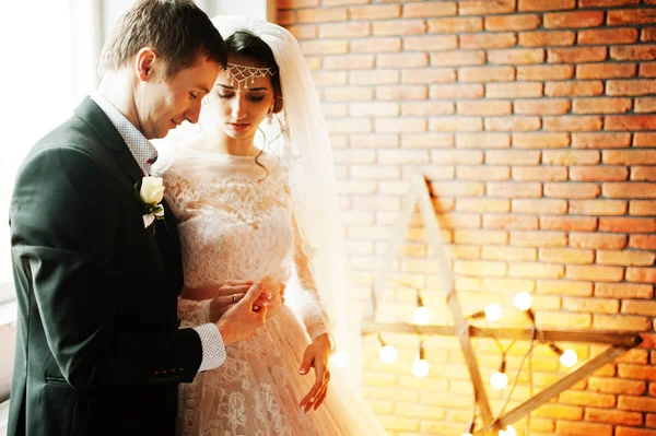 Çift yıldız şeklinde ışık ile tuğla duvara poz düğün.