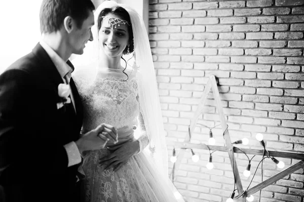 Pareja de boda posando contra pared de ladrillo con luz en forma de estrella . —  Fotos de Stock