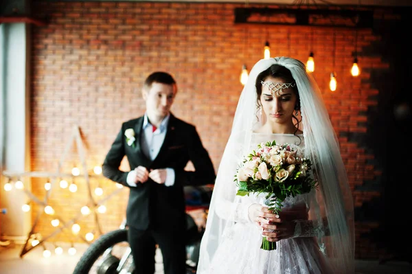 Geweldige bruidspaar poseren met een enorme oude motorfiets in een ro — Stockfoto