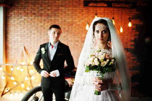 Geweldige bruidspaar poseren met een enorme oude motorfiets in een ro — Stockfoto