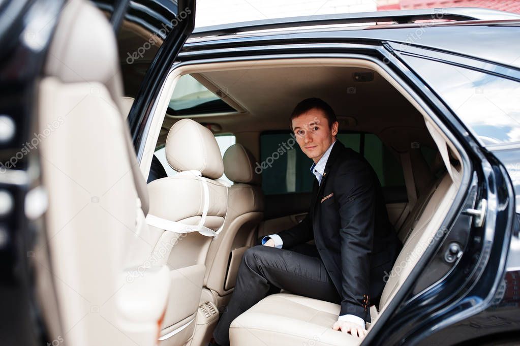 Portrait of a handsome groom sitting in the wedding car.