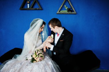 Triangula ile mavi duvara oturan muhteşem Düğün çifti