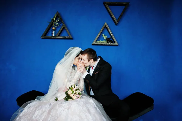 Mesés esküvői pár ült kék falnak triangula — Stock Fotó