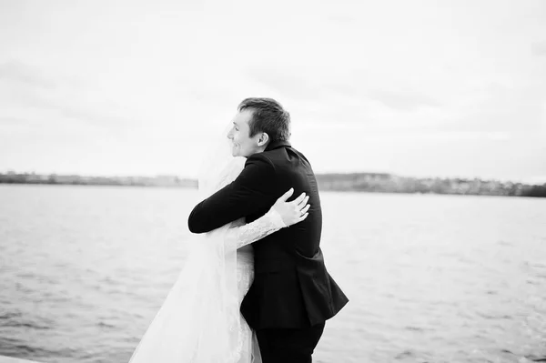 Novomanželský pár chůzi a lodě na břehu jezera na svého — Stock fotografie