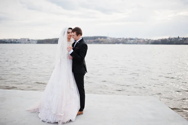 Couple nouvellement marié marchant et posant au bord du lac sur leur — Photo