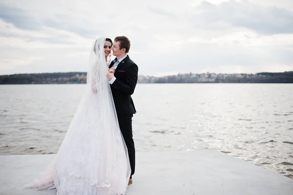 Couple nouvellement marié marchant et posant au bord du lac sur leur — Photo