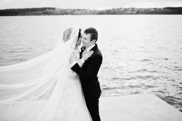 Couple nouvellement marié marchant et posant au bord du lac sur leur — Photo