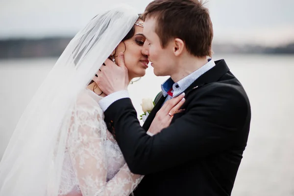 Photo en gros plan d'un couple de mariés embrassant au bord du lac . — Photo