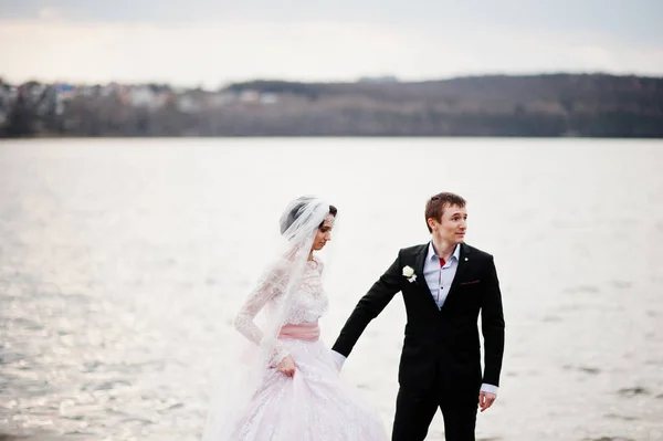 Couple nouvellement marié marchant et posant au bord du lac sur leur — Photo