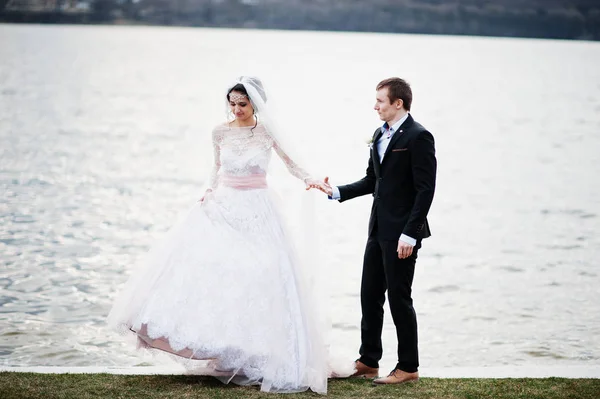 Couple nouvellement marié marchant et posant au bord du lac sur leur — Photo