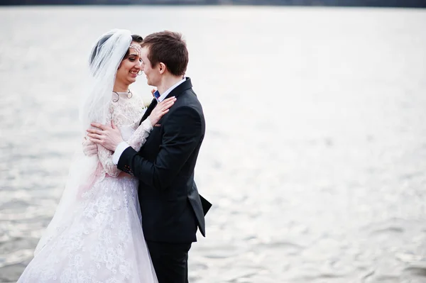 Couple nouvellement marié marchant et posant au bord du lac sur leur — Photo