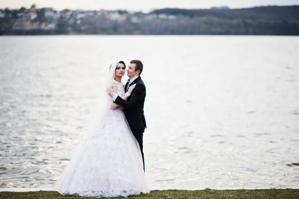 Couple nouvellement marié marchant et posant au bord du lac sur leur — Photo