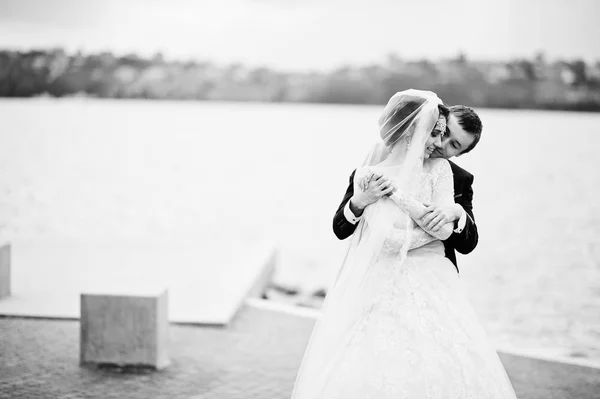 Couple nouvellement marié marchant et posant au bord du lac sur leur — Photo