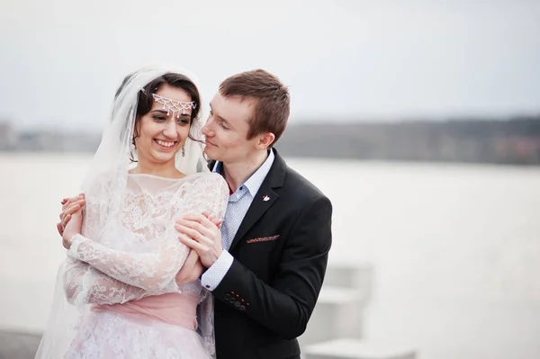 Couple nouvellement marié marchant et posant au bord du lac sur leur — Photo