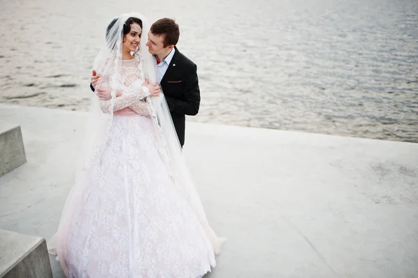 Couple nouvellement marié marchant et posant au bord du lac sur leur — Photo