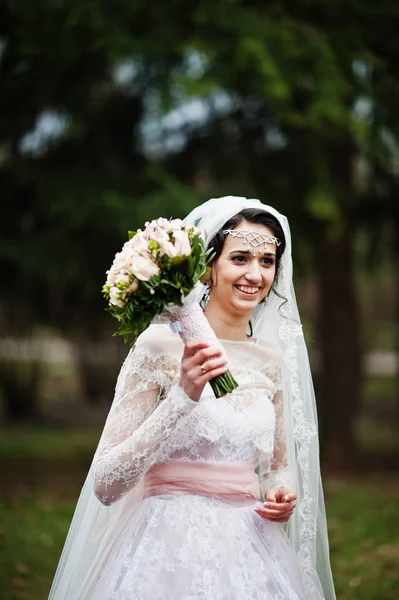 Portrét krásné nevěsty pózuje v parku s kyticí na — Stock fotografie