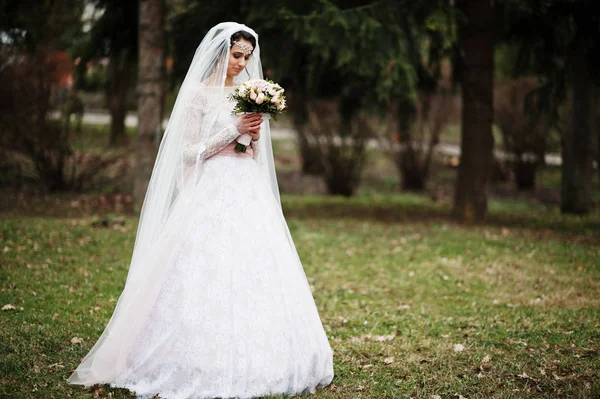 Portrait of a pretty bride posing in the park with a bouquet on — Stock Photo, Image