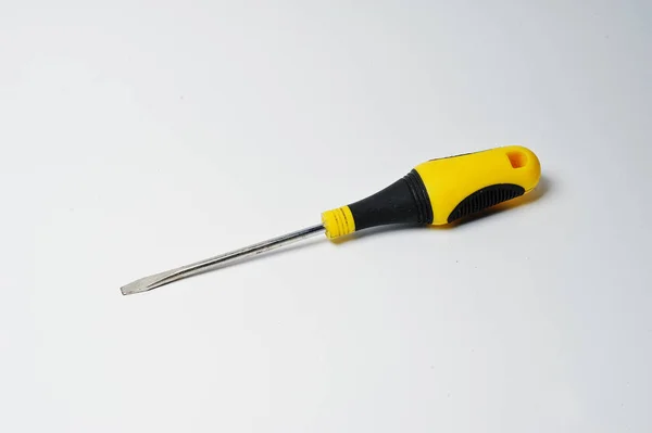 Close-up photo of black and yellow screwdriver on the white back — Stock Photo, Image