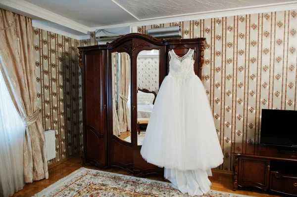 Свадебное платье висит на вешалке на шкафу в комнате . — стоковое фото