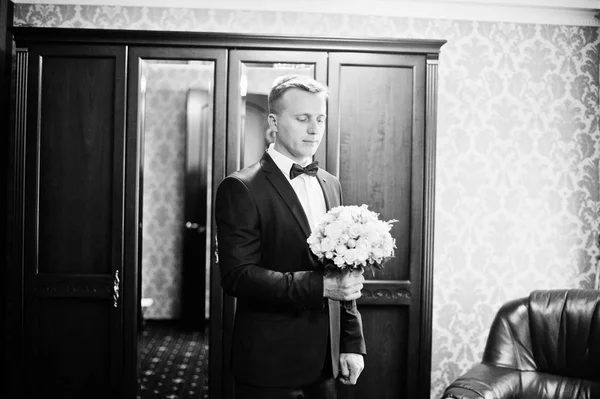 Portrait of a handsome groom posing with bridal bouquet in his c — Stock Photo, Image