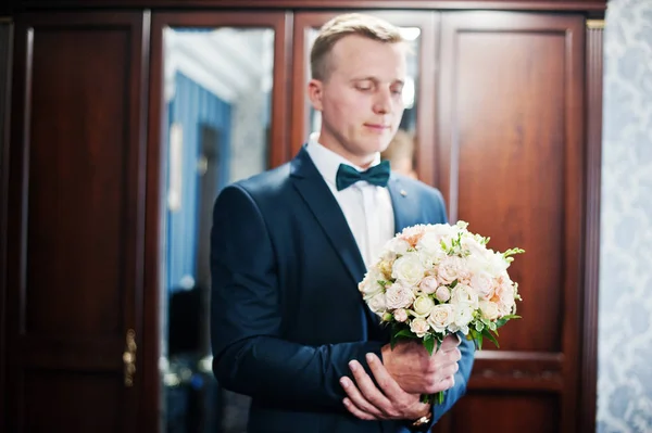 Retrato de un novio guapo posando con ramo de novia en su c —  Fotos de Stock