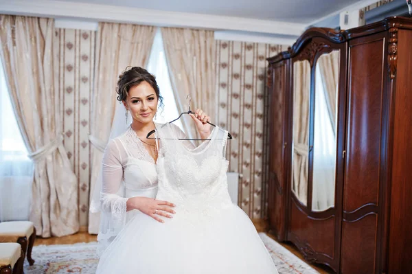 Портрет красивої нареченої позує з сукнею на вішалці — стокове фото
