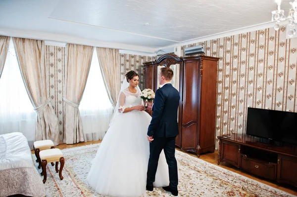 Bello sposo dando a sua moglie il suo bouquet da sposa al coperto . — Foto Stock
