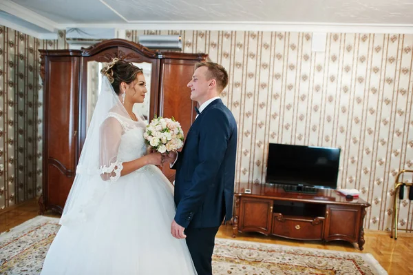 Fabelhaftes Hochzeitspaar posiert im Zimmer der Braut. — Stockfoto