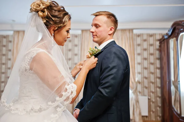 Attractive bride pinning buttonhole flower to the groom's jacket — Stock Photo, Image