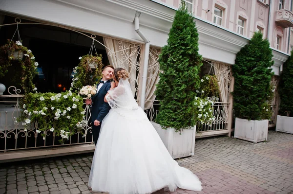 Newlyweds walking on the street of an old town with cafe and flo — Stock Photo, Image